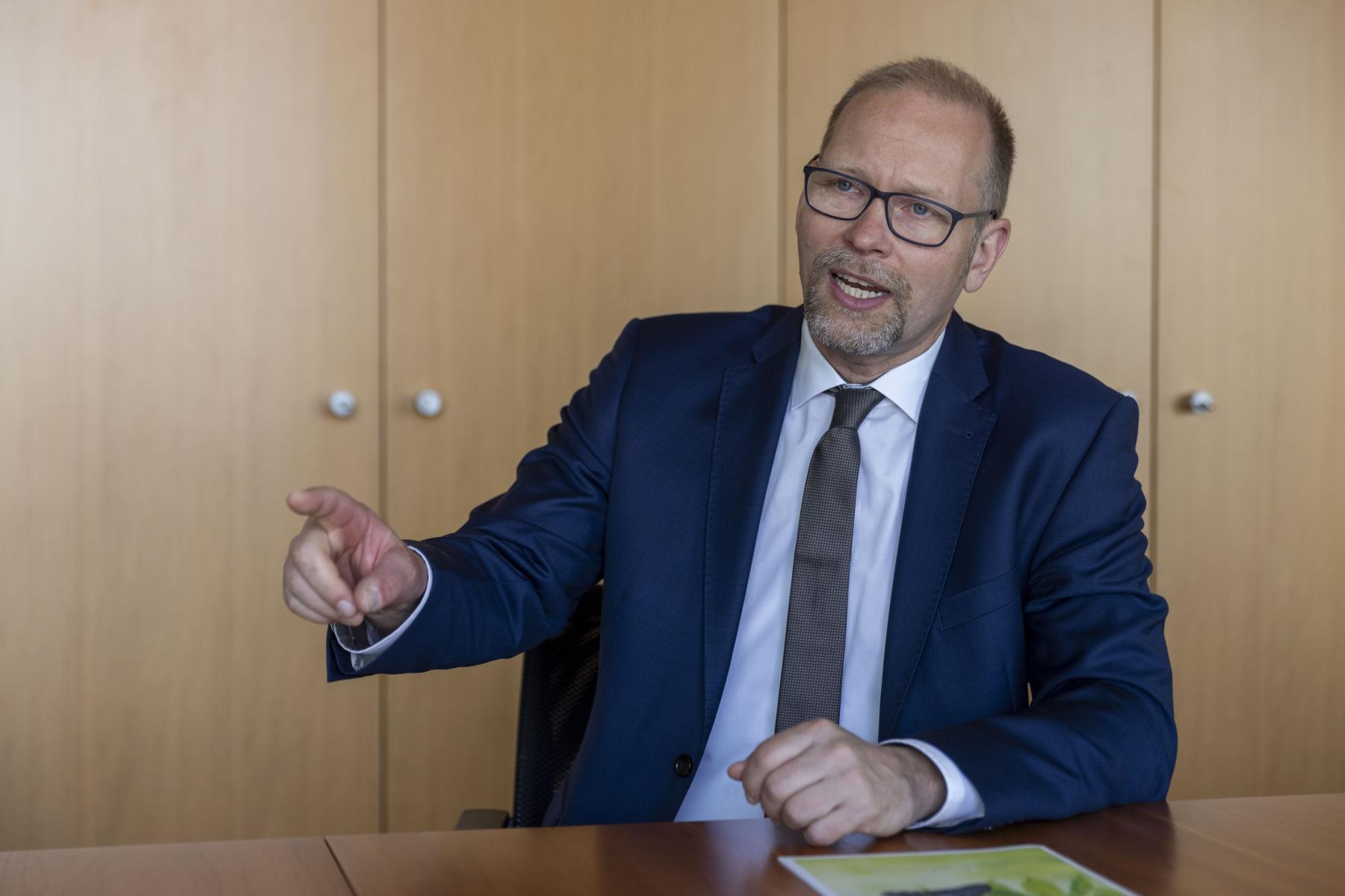 Mann sitzt mit erhobenem Zeigefinger am Tisch