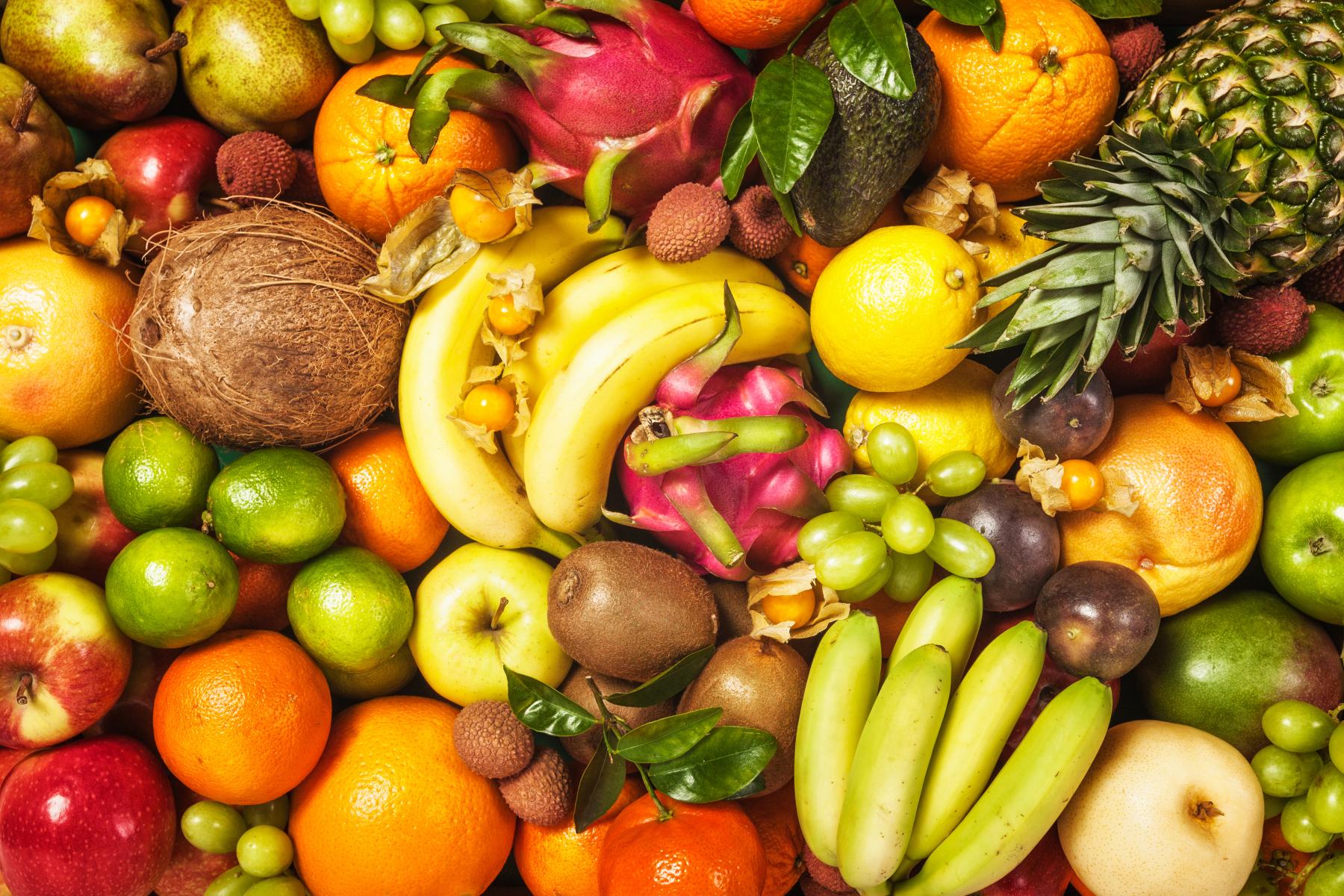 Verschiedene frische Früchte, darunter Bananen, Ananas, Äpfel, Zitrusfrüchte, Kiwis und Drachenfrüchte.
