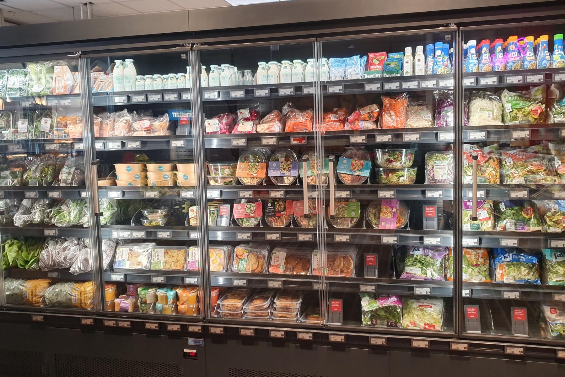 Kühlregal im Lebensmitteleinzelhandel mit verpackten Salaten, Gemüse und weiteren Convenience-Produkten.
