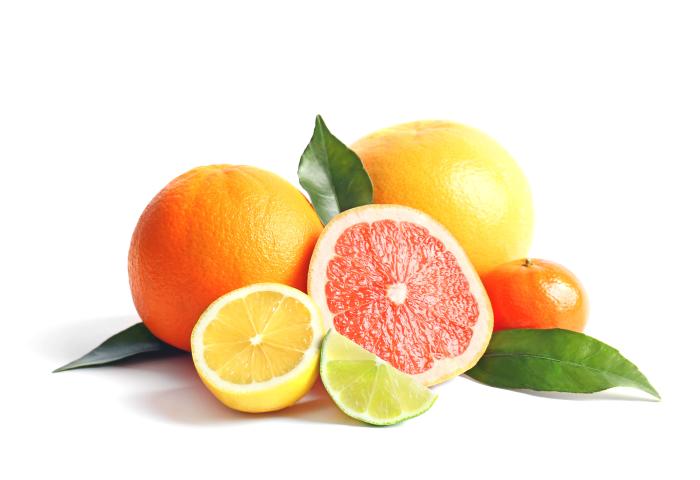Verschiedene Citrusfrüchte mit Blättern, darunter Orange, Grapefruit, Zitrone und Limette, einige halbiert