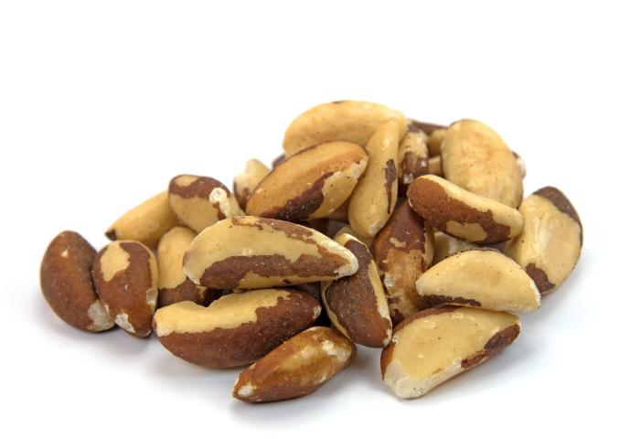 Eine Handvoll Paranüsse mit brauner Schale und cremefarbenem Inneren auf weißem Hintergrund