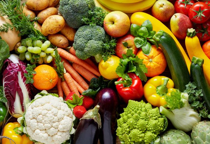 Verschiedene frische Gemüsesorten und Früchte, darunter Karotten, Paprika, Brokkoli, Tomaten, Auberginen, Blumenkohl, Zucchini, Trauben und Orangen