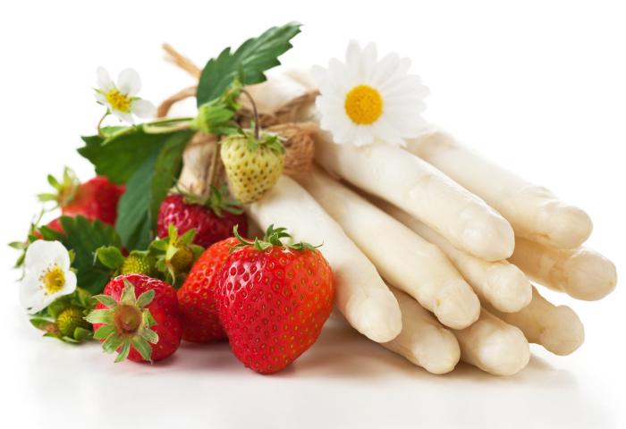 Weißer Spargel und frische Erdbeeren mit grünen Blättern und weißen Blüten