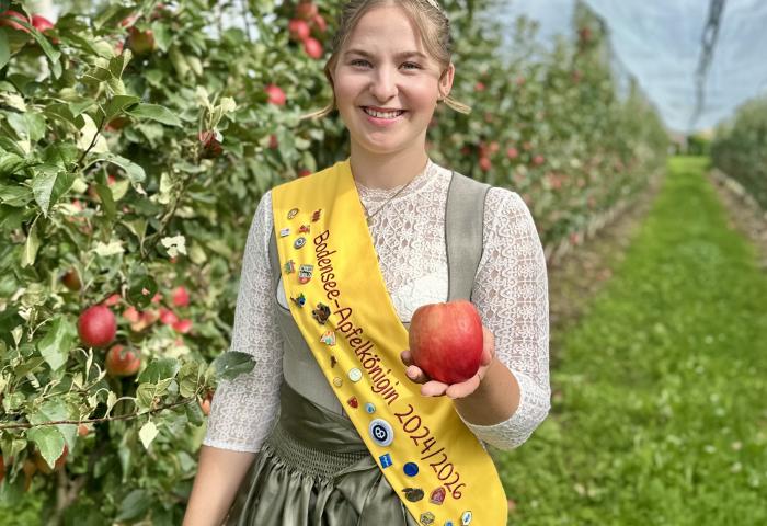 Apfelkönigin Emelie Witzigmann mit Apfel in der Hand in einer Apfelplantage
