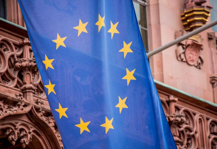 Europaflagge mit zwölf gelben Sternen im Kreis auf blauem Hintergrund vor einem historischen Gebäude