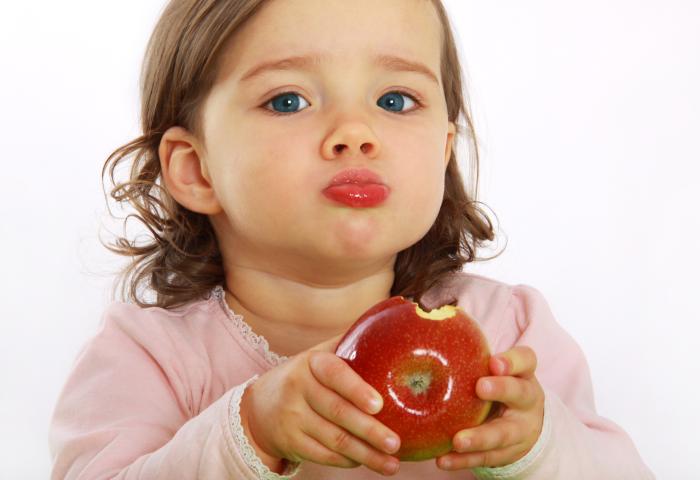 Ein Kind hält einen angebissenen roten Apfel in den Händen.