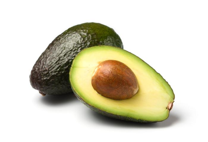 Eine ganze und eine halbe Avocado mit einem sichtbaren Kern in der Mitte.