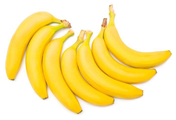 Sieben gelbe Bananen mit Stielansatz, angeordnet auf weißem Hintergrund