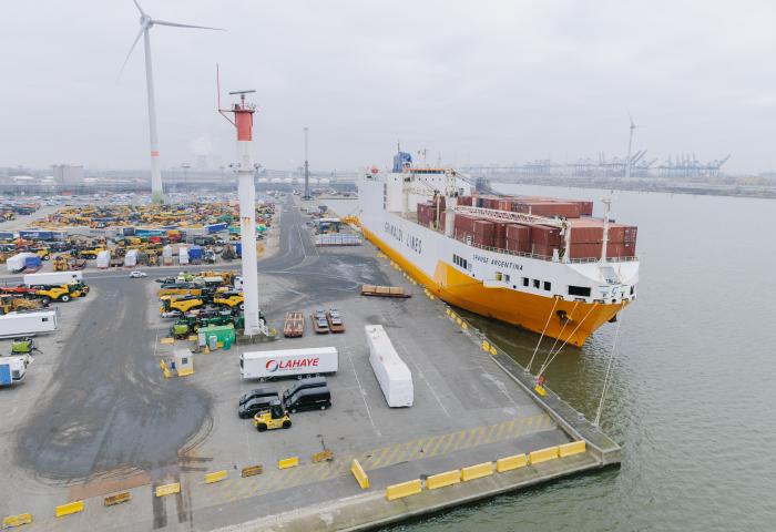 Großes Frachtschiff der Reederei Grimaldi Lines am Dock im Hafen von Antwerpen-Brügge, umgeben von Containern und Hafenanlagen
