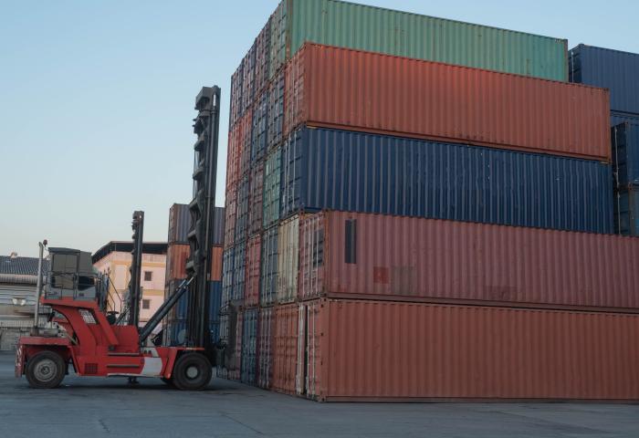 Gabelstapler hebt Container in einem Lager mit gestapelten Frachtcontainern