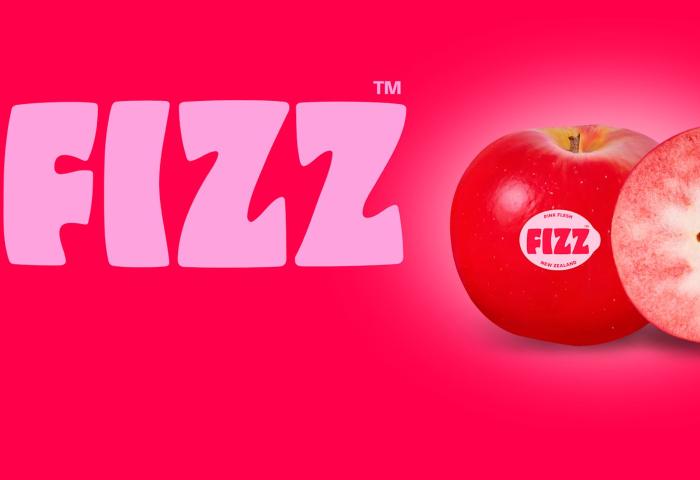 Markenname 'FIZZ' in pinker Schrift auf rotem Hintergrund neben einem halbierten, rotfleischigen Apfel mit sichtbaren Kernen