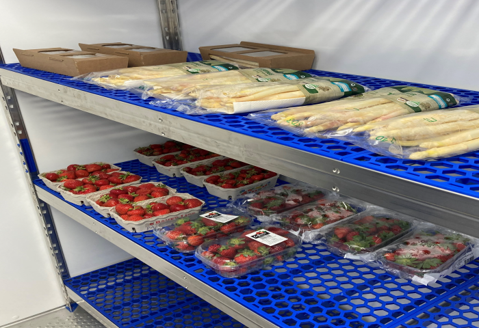 Regal im Kühlhaus mit verpacktem weißem Spargel oben und verschiedenen Verpackungen frischer Erdbeeren darunter