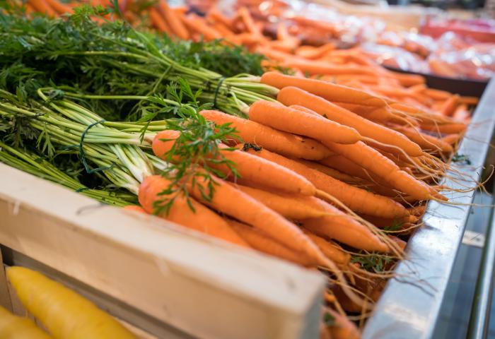 Frische orangefarbene Karotten mit grünen Blättern in einer Holzkiste