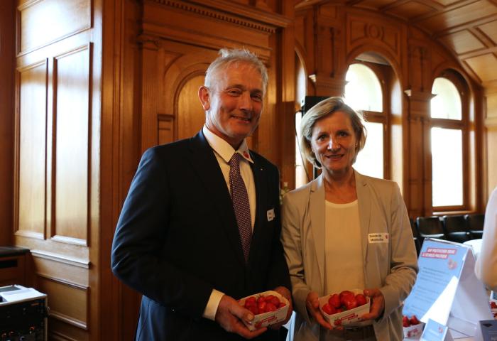 Simone de Montmollin und Jürg Hess stehen nebeneinander und halten jeweils eine Schale mit Erdbeeren