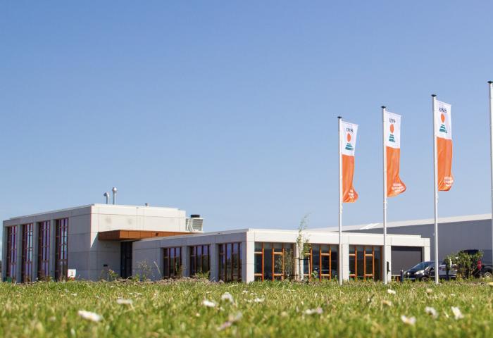 Forschungs- und Entwicklungszentrum mit Flachbau und vier Fahnen mit Firmenlogo auf grünem Rasen