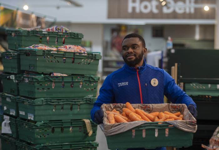 Mitarbeiter von Tesco mit einer Kiste Möhren