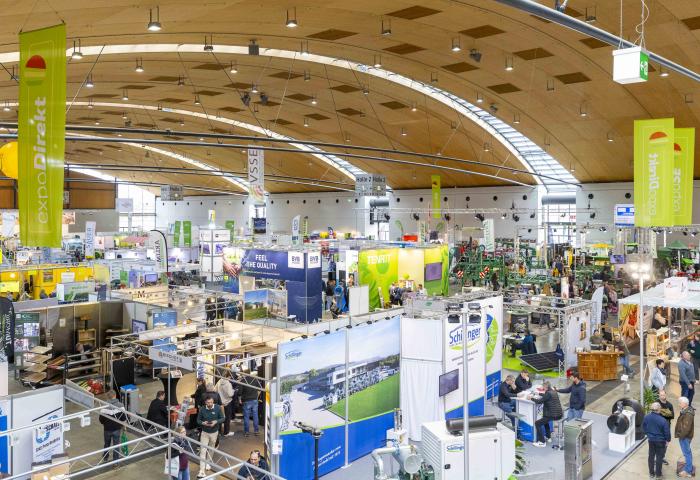 Blick auf eine Messehalle mit zahlreichen Ständen und Ausstellern. Über den Ständen hängen grüne Banner mit dem Text 'expoDirekt' und 'vsse'.