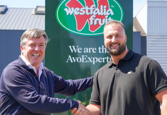 Wim Destoop und Carel van Krimpen schütteln sich vor einem Schild mit dem Logo von Westfalia Fruit die Hand