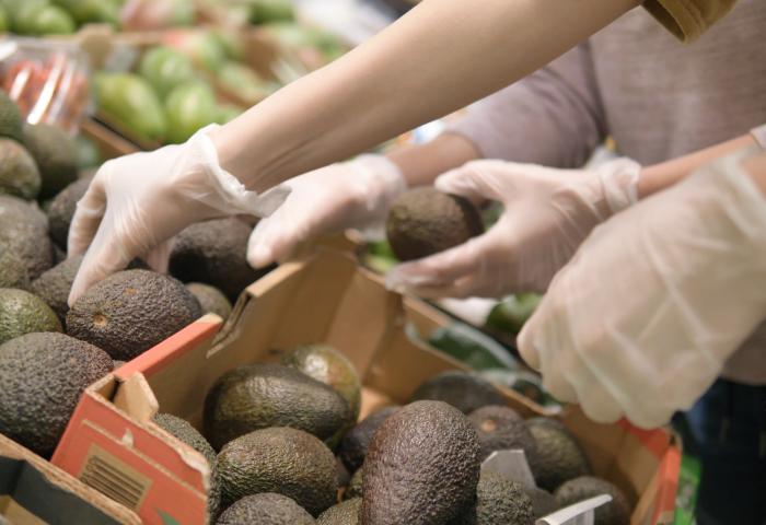 Hand greift nach Avocados in Kisten