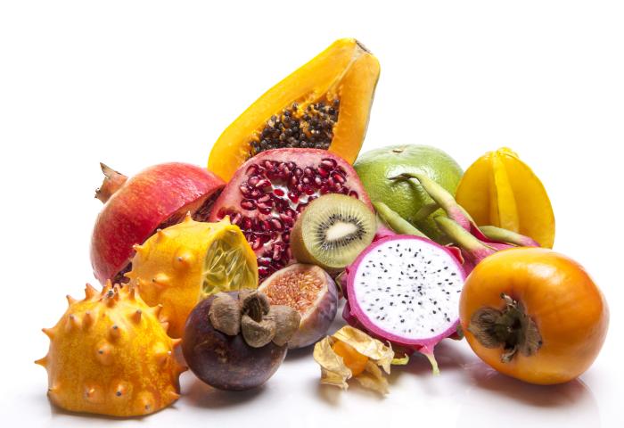 Eine Anordnung verschiedener exotischer Früchte, darunter: Papaya, Granatapfel, Kiwi, Drachenfrucht, Mangostan, Kiwano, Persimone
