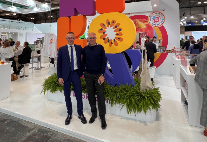 Fabio Zanesco links und Gerhard Dichgans stehen nebeneinander vor einem Messestand mit bunten, großen Buchstaben, die 'Kikokà' bilden