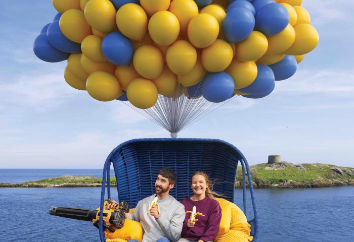Mann und Frau in einem Korb, der von Ballons getragen wird