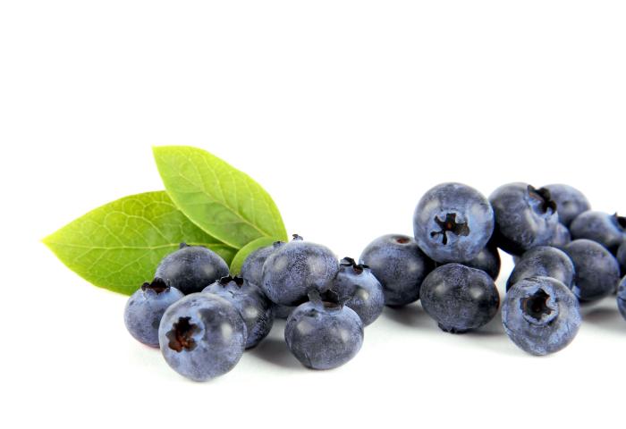 Eine Ansammlung von Heidelbeeren in verschiedenen Größen, einige mit grünen Blättern. Die Beeren sind rund und dunkelblau.