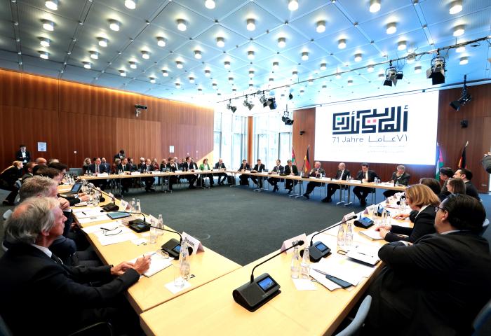 mehrere Teilnehmer, die in einem Konferenzraum um einen großen Tisch sitzen. Im Hintergrund ein Banner mit '71 Jahre LoLaCV'.