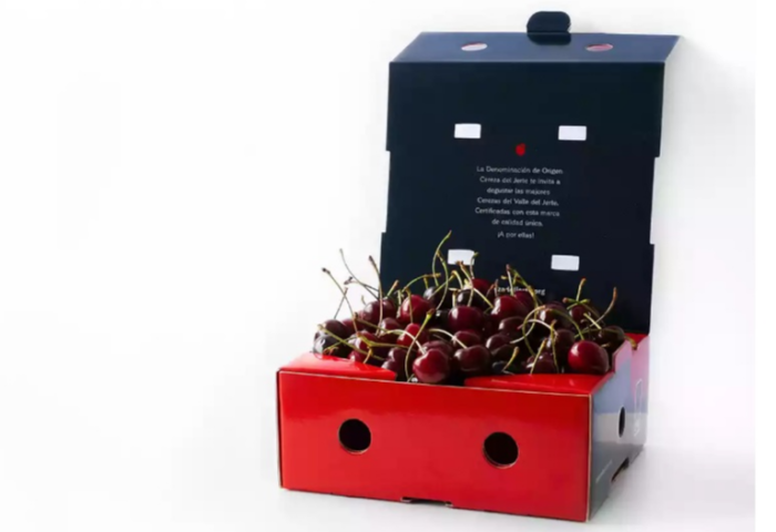 Rote Kirschen in einer offenen, roten und schwarzen Verpackung. Auf der Innenseite der Box steht der Text: 'La Denominación de Origen Cereza del Jerte.'
