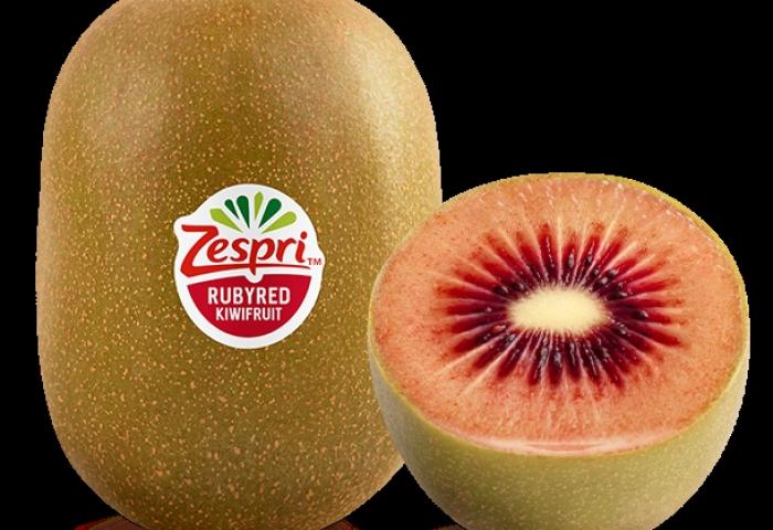 Zespri Ruby Red Kiwi, ovaler, braun-grüner Fruchtkörper mit Aufkleber 'Zespri Rubyred Kiwifruit', halbierte Frucht zeigt rotes Fruchtfleisch mit weißem Kern.