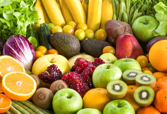 Eine Vielzahl von frischem Obst und Gemüse, darunter Bananen, Äpfel, Orangen, Avocados, Kiwis, Granatäpfel und verschiedene Salatsorten.