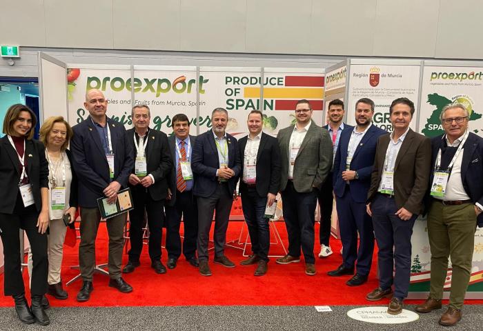 Gruppe von Personen steht vor einem Messestand mit den Aufschriften 'proexport', 'PRODUCE OF SPAIN' und 'Region de Murcia'
