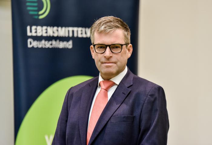 René Püchner steht vor einem Banner mit dem Text 'LEBENSMITTEL Deutschland'.