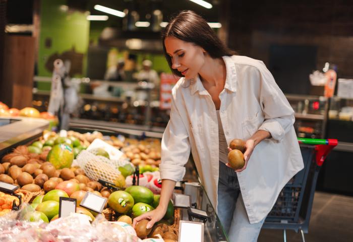 Frau kauft Kiwi im Supermarkt