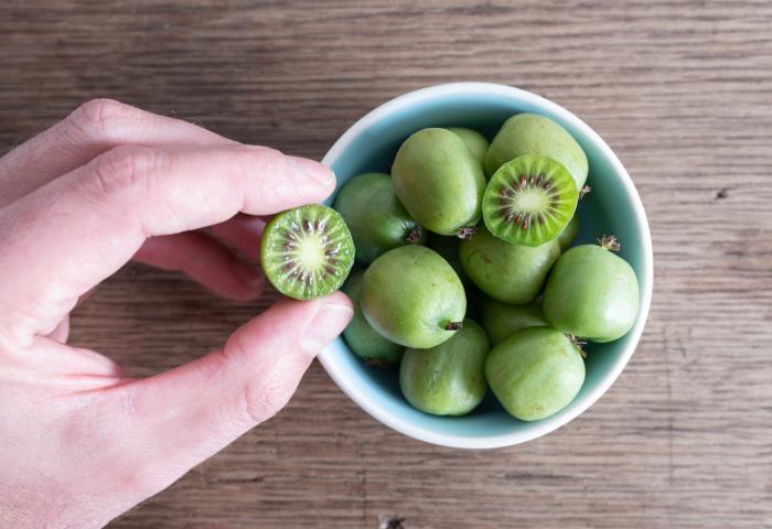 Hand greift in Schale mit Kiwibeeren