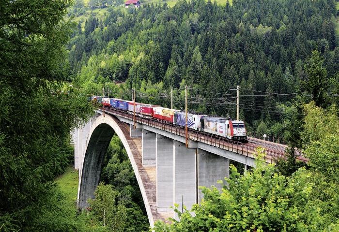 Gütertransport auf der Schiene fährt über eine Brücke. 