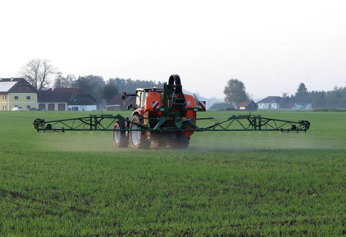 Traktor verteilt Pflanzenschutzmittel auf dem Feld