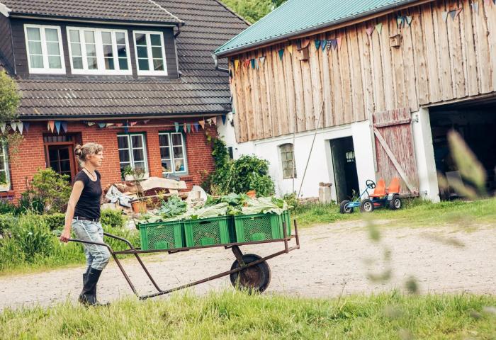 Bäuerin schiebt Schubkarre mit Gemüse