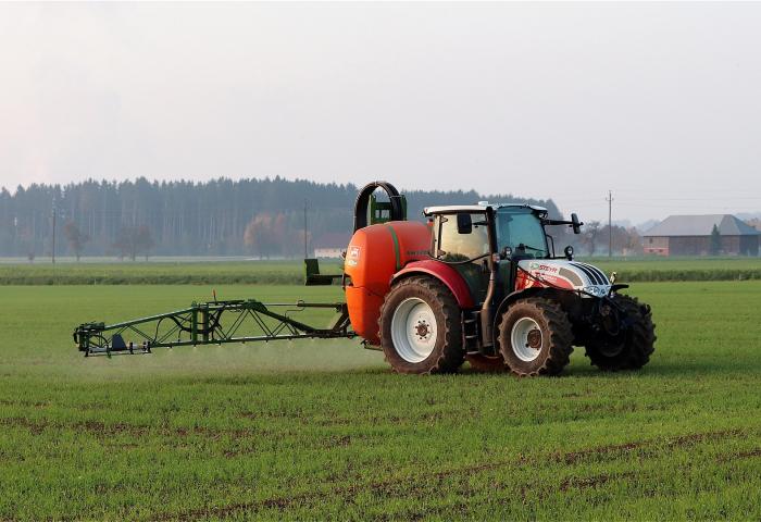 Traktor verteilt Pflanzenschutzmittel auf dem Feld