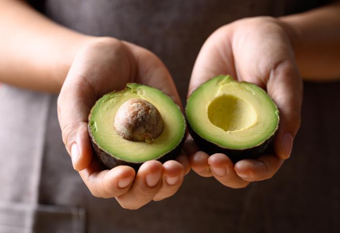 Hände halten aufgeschnittene Avocado