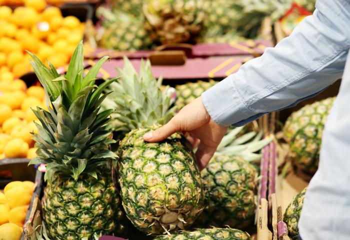 Hand greift nach Ananas im Regal