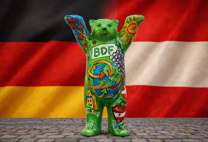 Buddy Bär vor deutscher und österreichischer Flagge