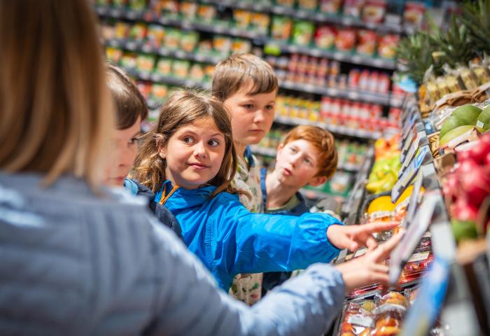 Kinder zeigen im Supermarkt auf Obst und Gemüse