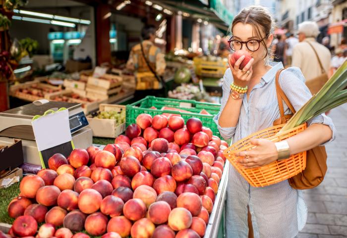 Frau riecht an Marktstand an Obst