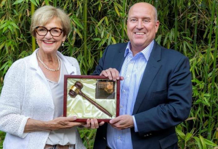 Mann und Frau halten Bilderrahmen mit Holzhammer in der Hand