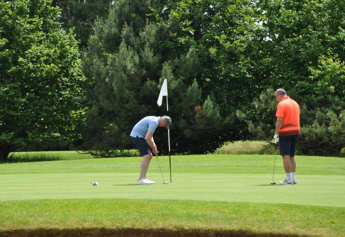 Zwei Menschen stehen vor einem Golfloch