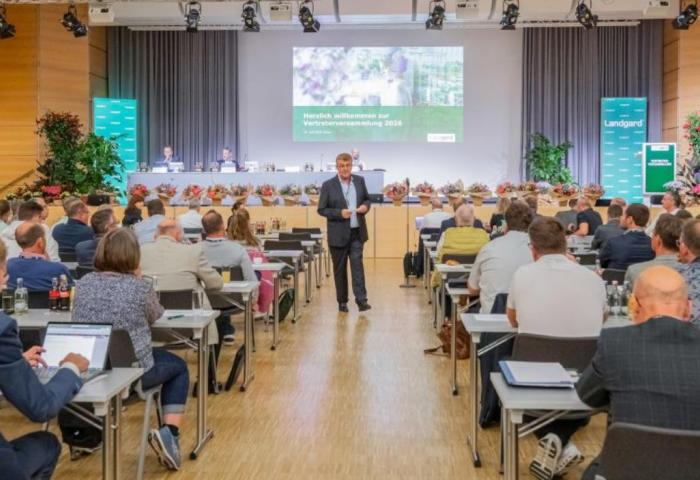 Menschen sitzen in Vortragsraum und schauen auf Folien an der Wand