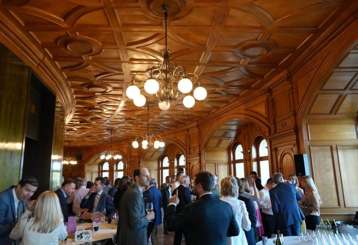 Menschen in altem Saal mit Getränken in der Hand