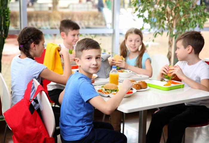Kinder sitzen mit Essen am Tisch