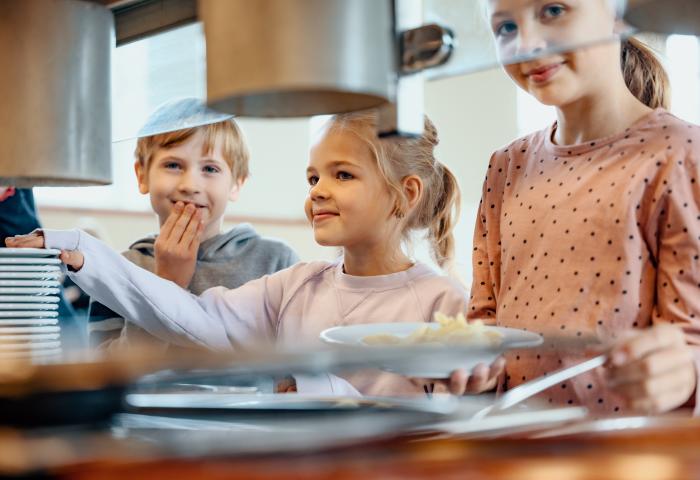 Kinder stehen an Bedientheke für Essen
